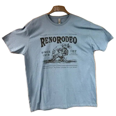 A light blue short-sleeve graphic t-shirt hanging on a wooden hanger against a wood-paneled door. The shirt features a black graphic print with the text 'RENORODEO' and 'SINCE 1919'.